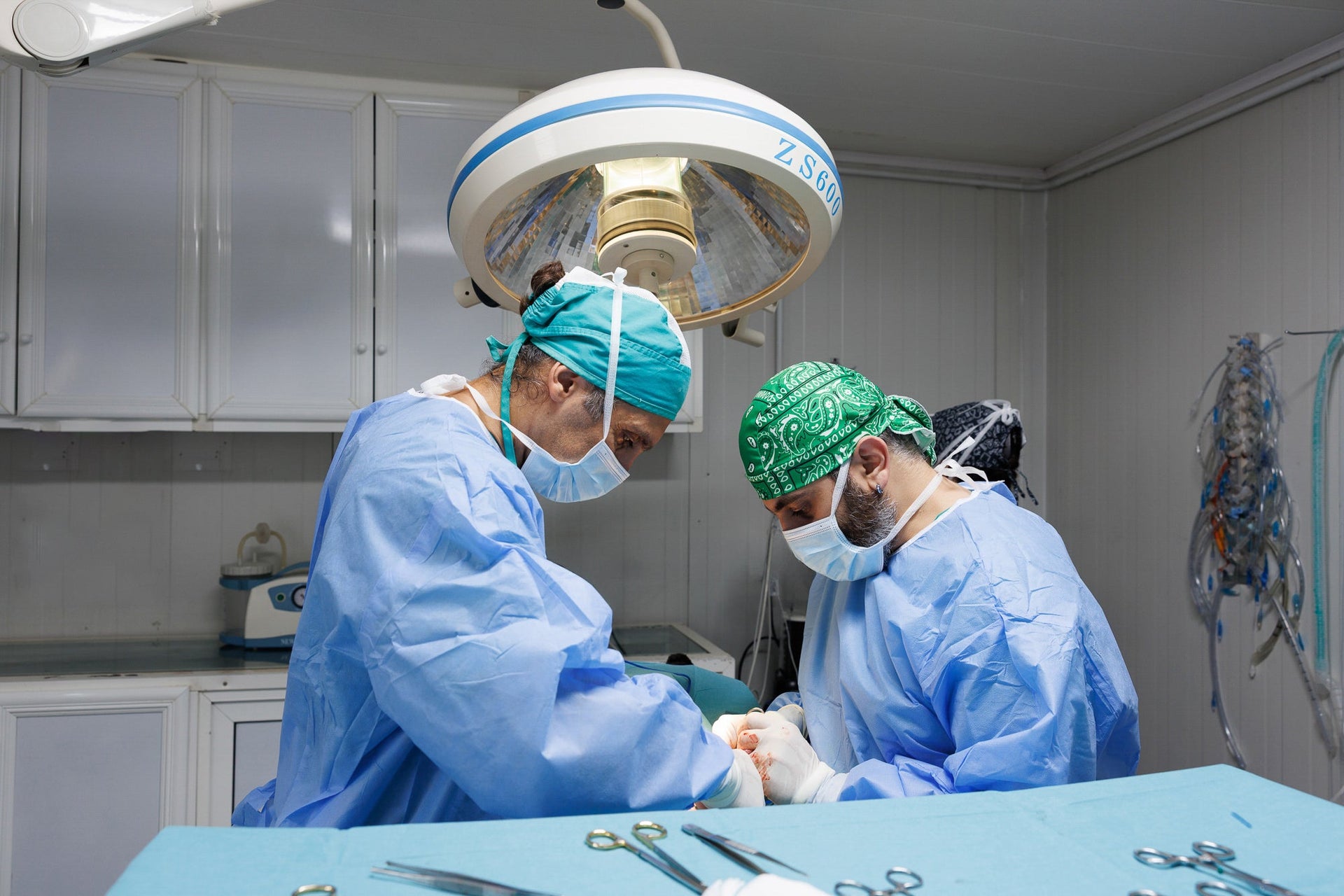 Two surgeons in an operating room with surgical instruments on a table.