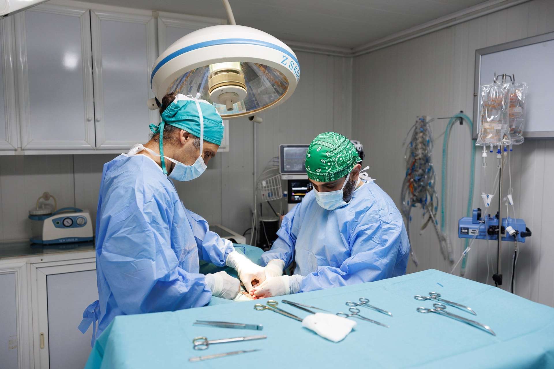 Two surgeons in an operating room with medical equipment.