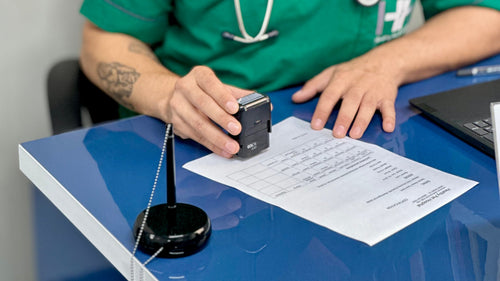 Doctor in green scrubs with a stethoscope taking notes at a desk.